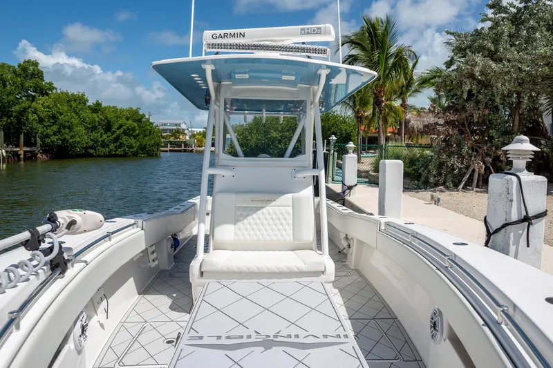 Slide: The Image of 2021 Invincible 33 Open Fisherman boat docked by lush greenery and clear skies. - 16