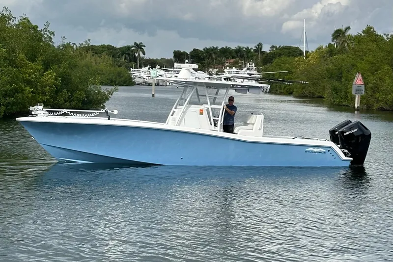 Slide: The Image of 2021 Invincible 33 Open Fisherman boat on a calm waterway, surrounded by lush greenery. - 4