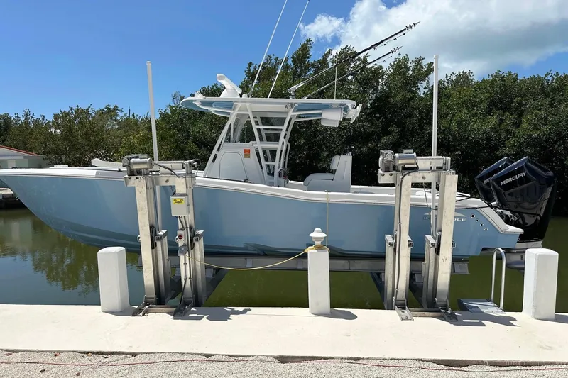 Slide: The Image of 2021 Invincible 33 Open Fisherman boat on lift, featuring sleek design and dual Mercury engines. - 5