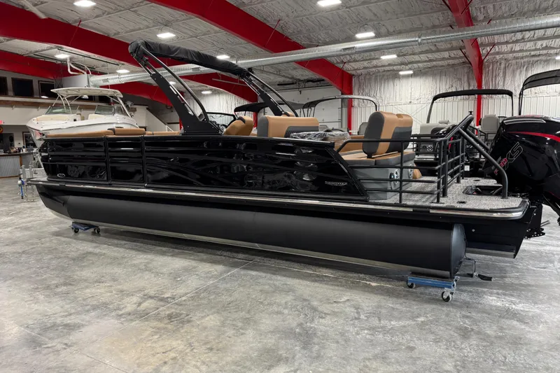 Slide: The Image of 2026 Sylvan L5 DLZ pontoon boat in showroom, featuring sleek black design and tan seating. - 3