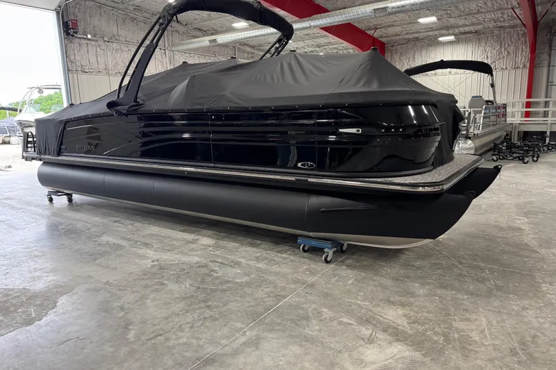 Slide: The Image of 2026 Sylvan L5 DLZ pontoon boat in a showroom, covered and ready for display. - 5