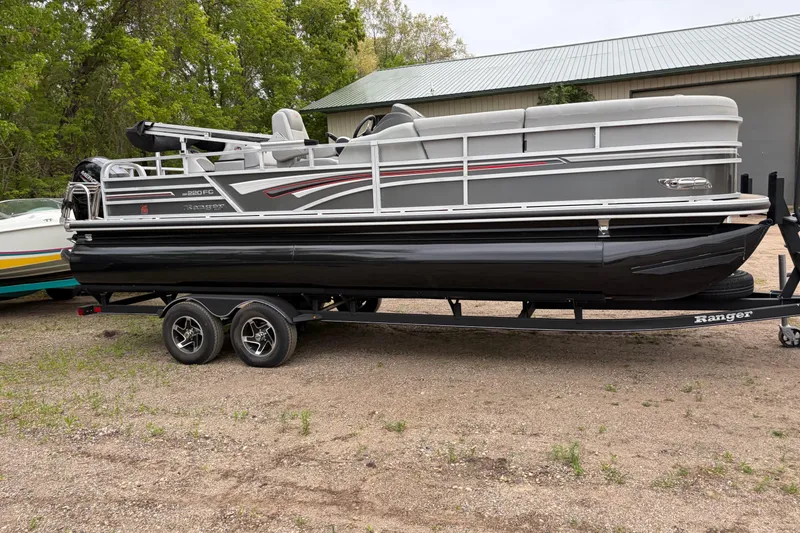 Slide: The Image of 2023 Ranger 220FC pontoon boat on trailer, parked outdoors near a building. - 3