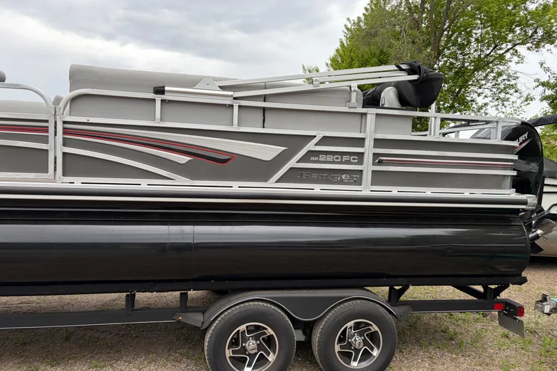 Slide: The Image of 2023 Ranger 220FC pontoon boat on trailer, side view with sleek design. - 4