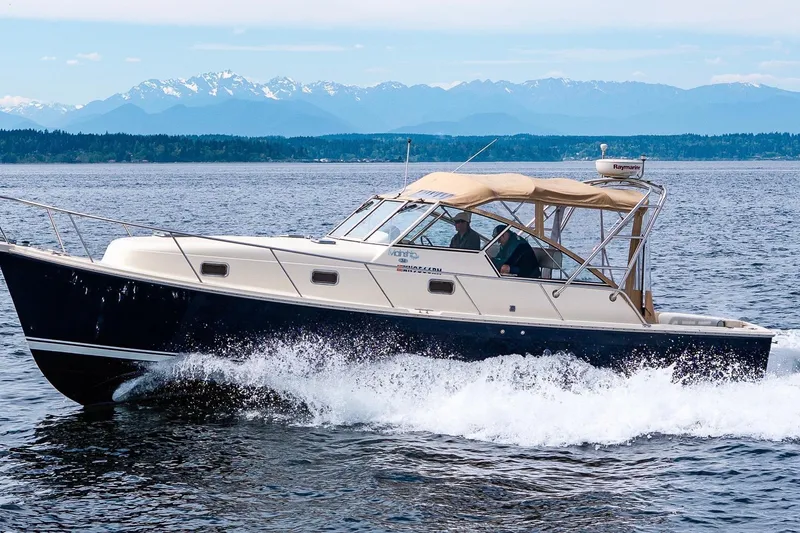 The Image of 2004 Mainship Pilot 34 cruising on open water with scenic Olympic Mountains in the background. - 0