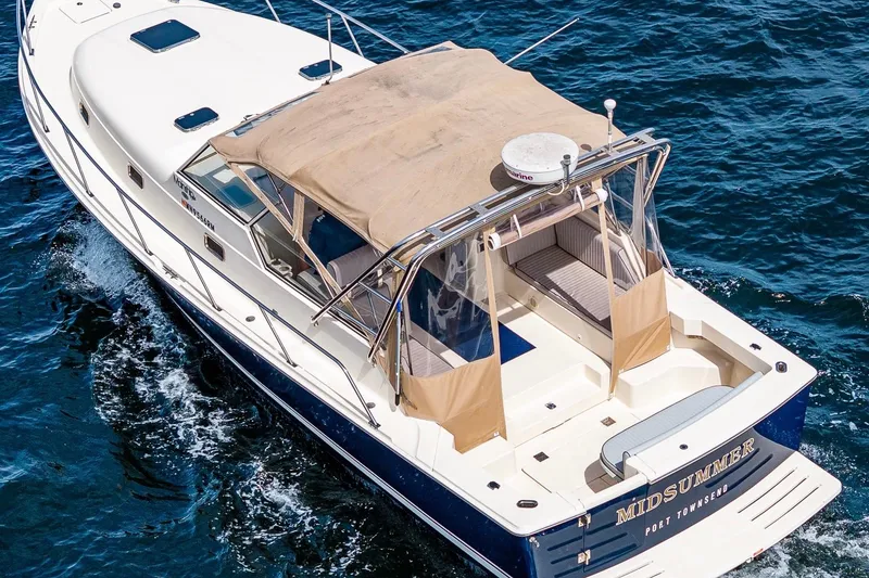 Slide: The Image of 2004 Mainship Pilot 34 cruising on open water, featuring a spacious deck and canopy. - 10