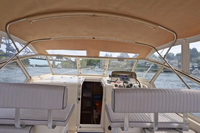 Slide: The Image of 2004 Mainship Pilot 34 boat interior with helm, seating, and waterway view. - 17