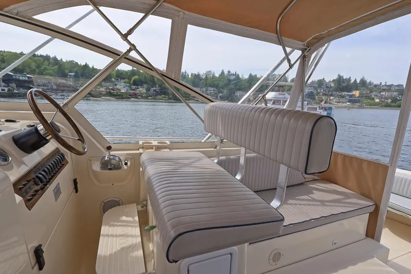Slide: The Image of 2004 Mainship Pilot 34 boat interior with helm, seating, and waterfront view. - 19
