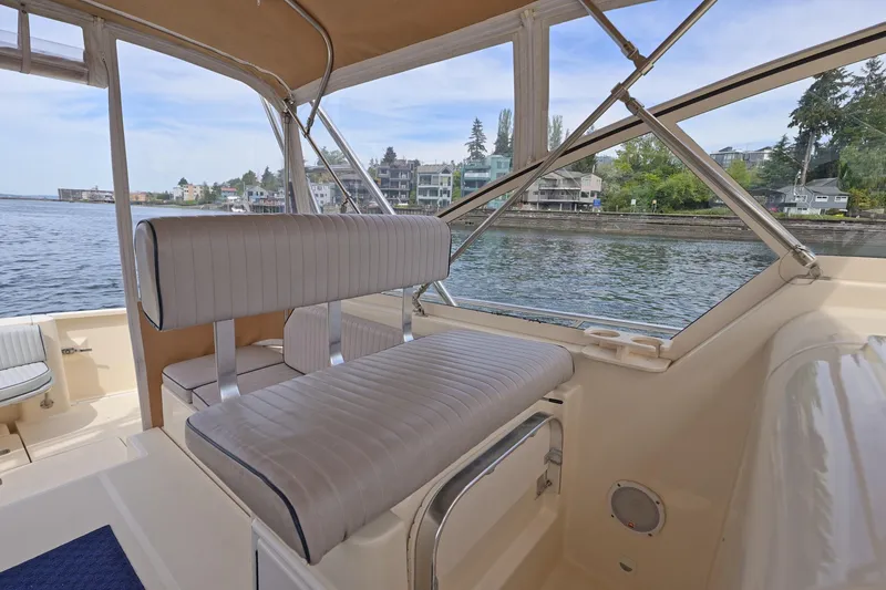 Slide: The Image of 2004 Mainship Pilot 34 boat interior with waterfront view, featuring comfortable seating and clear windows. - 20