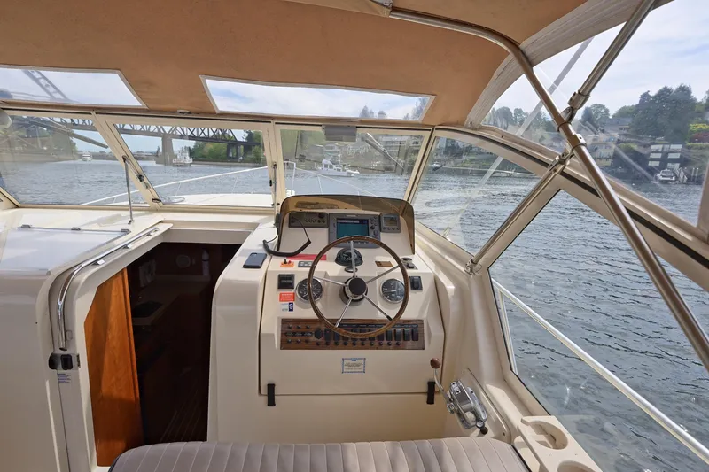Slide: The Image of 2004 Mainship Pilot 34 helm with scenic waterway view, featuring classic steering and navigation controls. - 21
