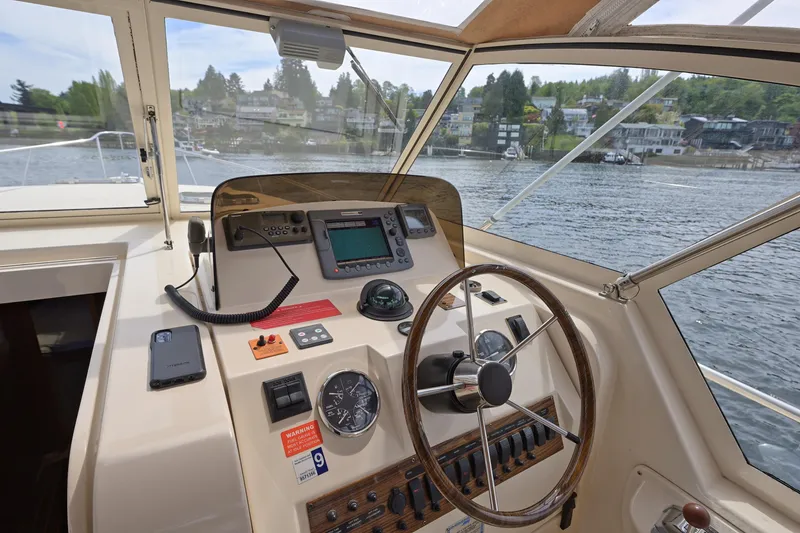 Slide: The Image of 2004 Mainship Pilot 34 helm with steering wheel, navigation controls and waterfront view. - 22