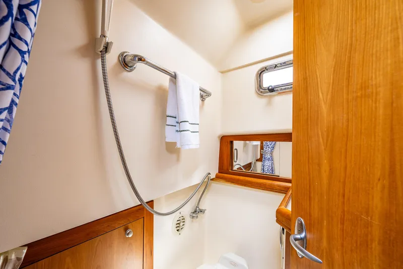 Slide: The Image of 2004 Mainship Pilot 34 bathroom with shower, towel rack and wooden cabinetry. - 28