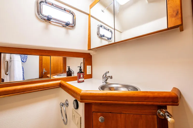 Slide: The Image of 2004 Mainship Pilot 34 yacht bathroom with wooden cabinetry and stainless steel sink. - 29