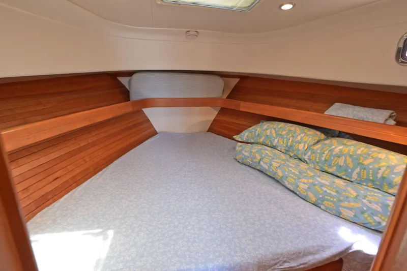 Slide: The Image of Cozy cabin interior of 2004 Mainship Pilot 34 with wooden accents and patterned bedding. - 31