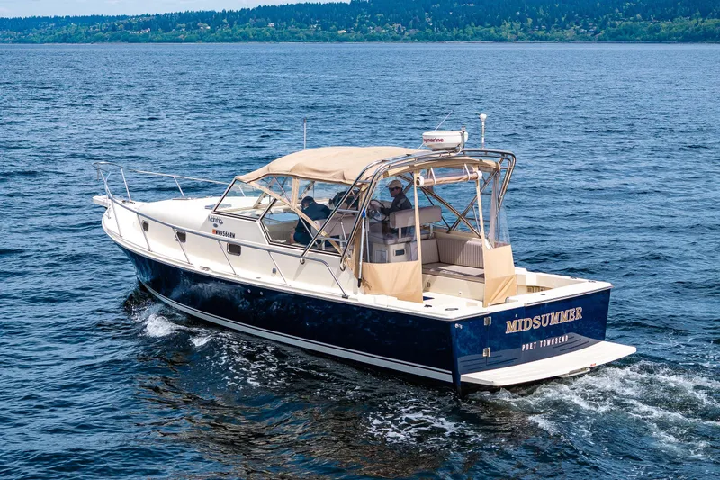 Slide: The Image of 2004 Mainship Pilot 34 boat cruising on a scenic Puget Sound with lush green shoreline. - 6