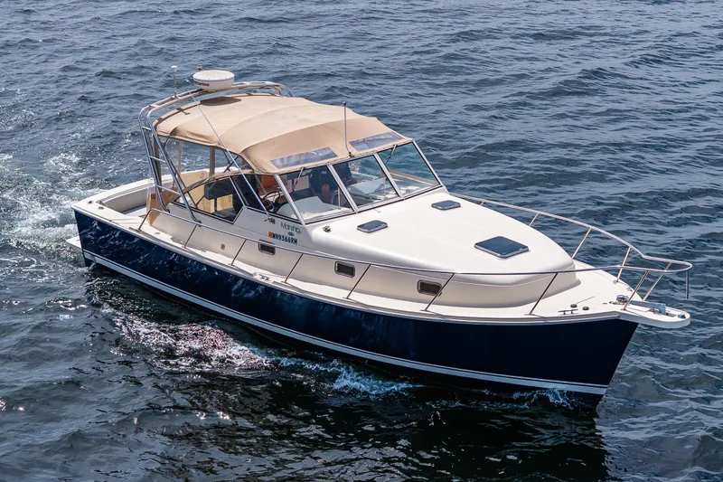 Slide: The Image of 2004 Mainship Pilot 34 cruising on open water, featuring a sleek design and beige canopy. - 7