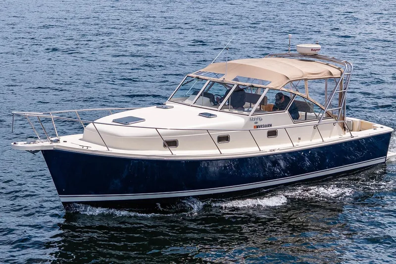 Slide: The Image of 2004 Mainship Pilot 34 cruising on open water, featuring a sleek design and beige canopy. - 8