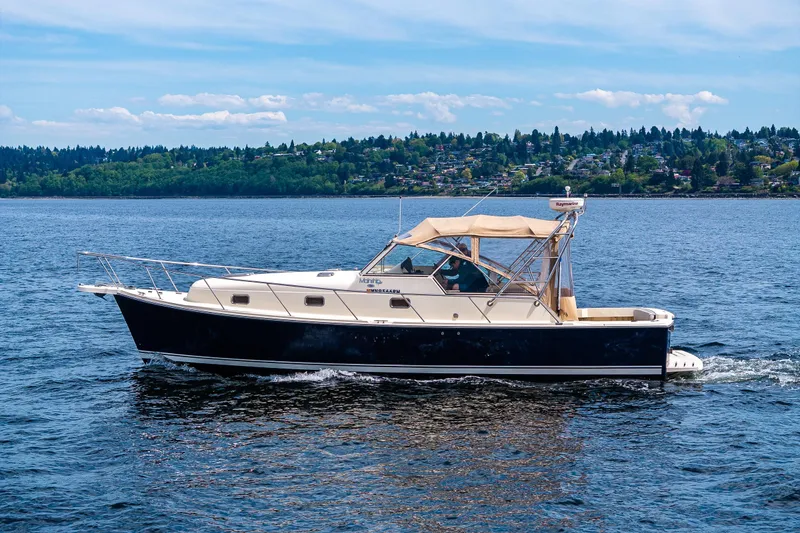 Slide: The Image of 2004 Mainship Pilot 34 cruising on the scenic Puget Sound with forested shoreline. - 9