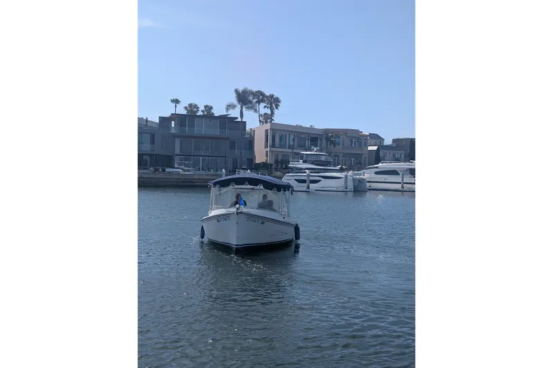 Slide: The Image of 2007 Duffy Cuddy Cabin 22 boat cruising in a marina with modern waterfront homes. - 24
