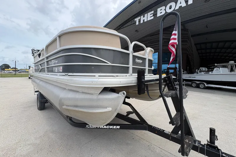 Slide: The Image of 2016 Sun Tracker Party Barge 20 DLX pontoon boat on trailer, parked outside a boat dealership. - 10