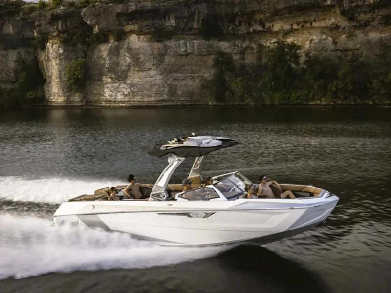 The Image of 2025 Tigé 25ZX boat cruising on a serene lake with cliff backdrop. - 0
