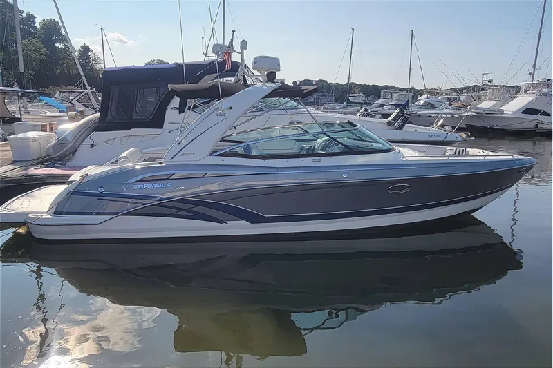 Slide: The Image of 2016 Formula 310 Bowrider boat docked in a marina, reflecting on calm water. - 11