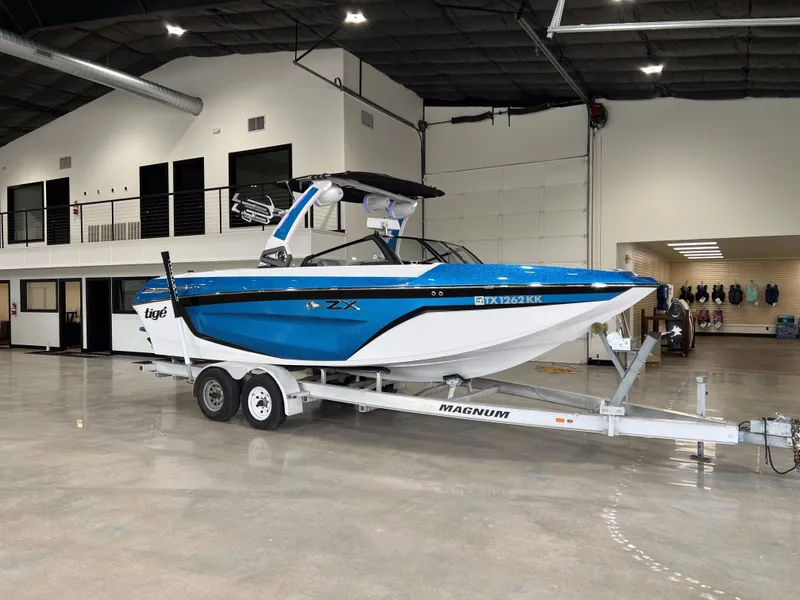 The Image of 2021 Tigé 25ZX boat on trailer inside a showroom. - 1