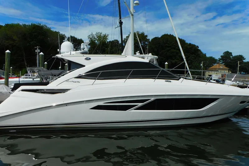 Slide: The Image of 2013 Sea Ray 510 Sundancer yacht docked in a marina, surrounded by trees and buildings. - 2