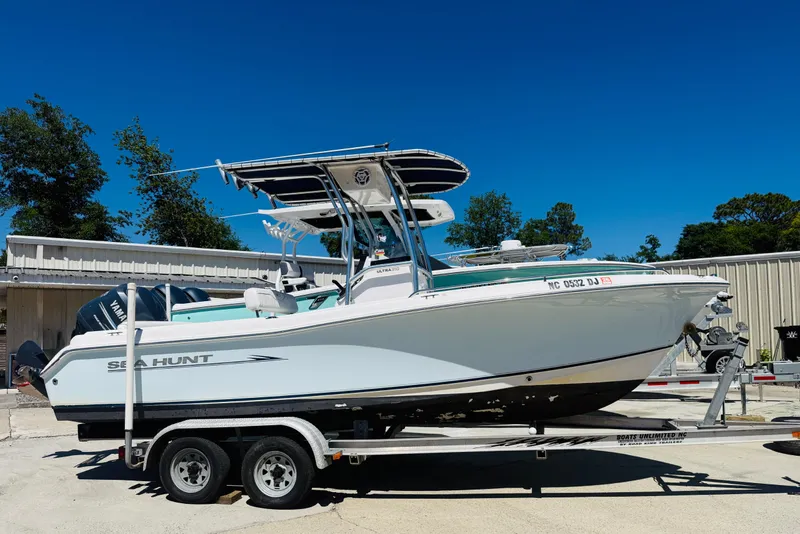 The Image of 2008 Sea Hunt Ultra 210 boat on trailer, parked outdoors under clear blue sky. - 1