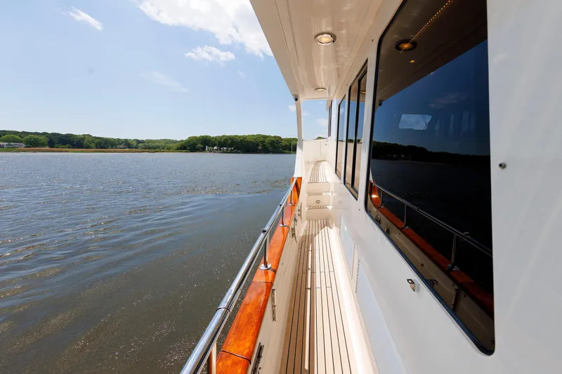 Slide: The Image of 2007 Grand Banks 59 Aleutian RP yacht cruising on a serene lake under a clear sky. - 20