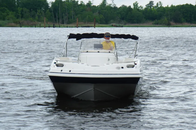Slide: The Image of 2015 Hurricane SunDeck Sport 231 OB boat cruising on a lake with a person steering. - 1