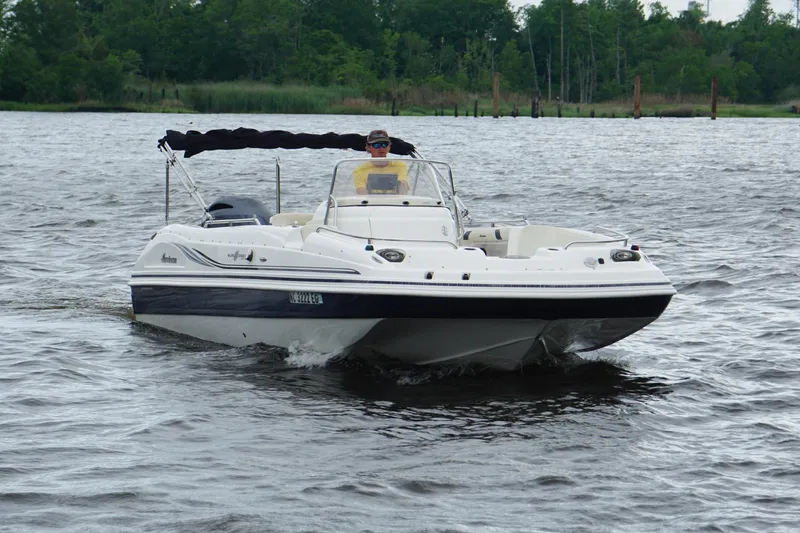 Slide: The Image of 2015 Hurricane SunDeck Sport 231 OB cruising on a lake with lush greenery in the background. - 18