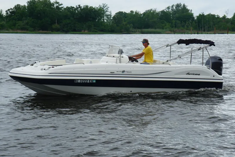 Slide: The Image of 2015 Hurricane SunDeck Sport 231 OB boat cruising on a lake with a person steering. - 19