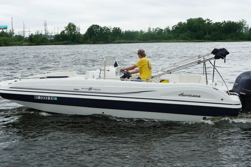 Slide: The Image of 2015 Hurricane SunDeck Sport 231 OB boat cruising on a lake with a person steering. - 21