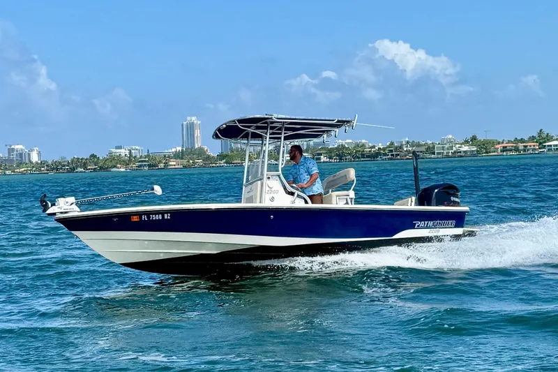 The Image of 2012 Pathfinder 2200 TRS boat cruising on blue waters near a coastal cityscape. - 0