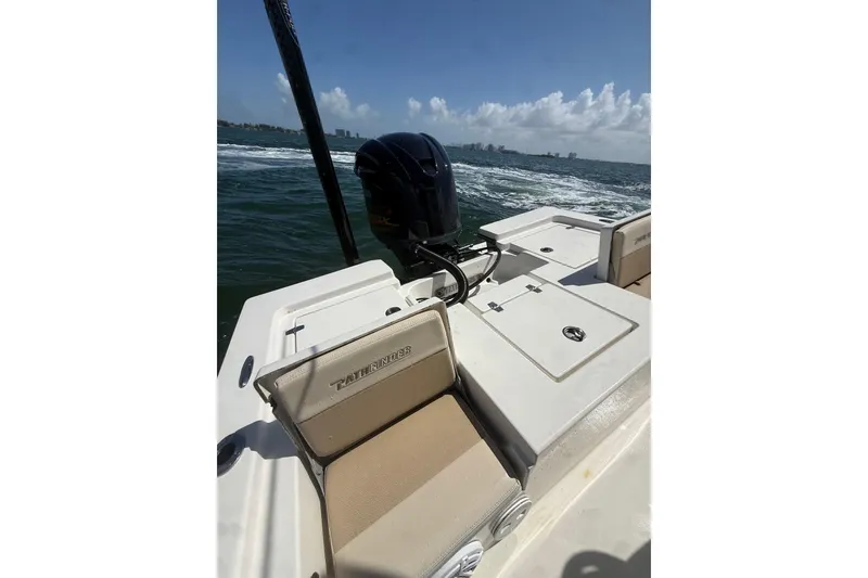 Slide: The Image of 2012 Pathfinder 2200 TRS boat on water, featuring seating and motor, under clear skies. - 13