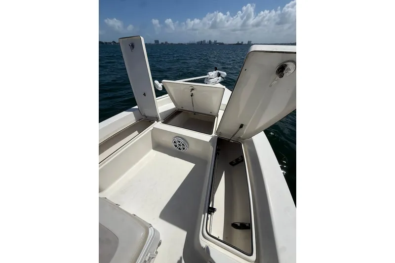 Slide: The Image of 2012 Pathfinder 2200 TRS boat with open storage compartments on calm water. - 15