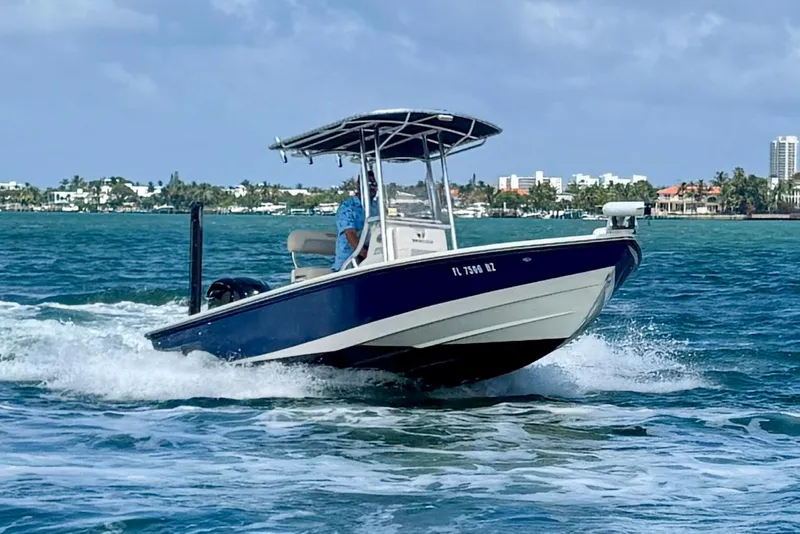 Slide: The Image of 2012 Pathfinder 2200 TRS boat cruising on blue ocean near city skyline. - 2