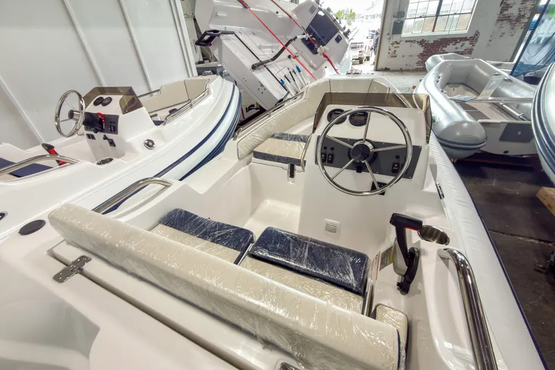 Slide: The Image of 2024 AB Inflatables Nautilus 13 boat interior with steering wheel and seating in showroom. - 2