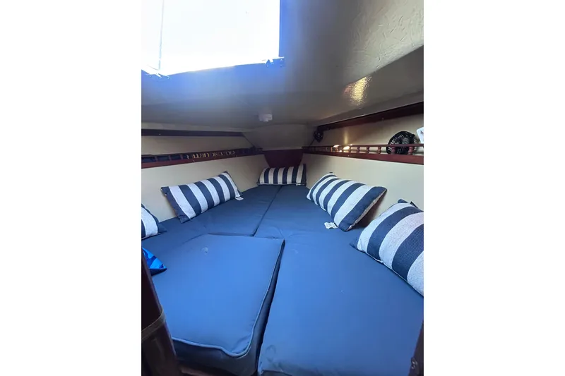 Slide: The Image of Cozy interior cabin of 1981 Catalina 30 sailboat with striped pillows and blue cushions. - 10