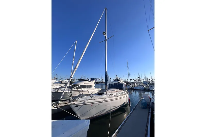 Slide: The Image of 1981 Catalina 30 sailboat docked in a marina under a clear blue sky. - 3
