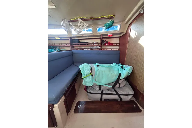Slide: The Image of Interior of a 1981 Catalina 30 sailboat with blue seating and storage bags. - 7