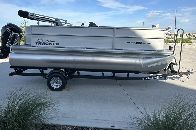 Slide: The Image of 2026 Sun Tracker Party Barge 16 DLX pontoon boat on trailer, parked outdoors. - 75