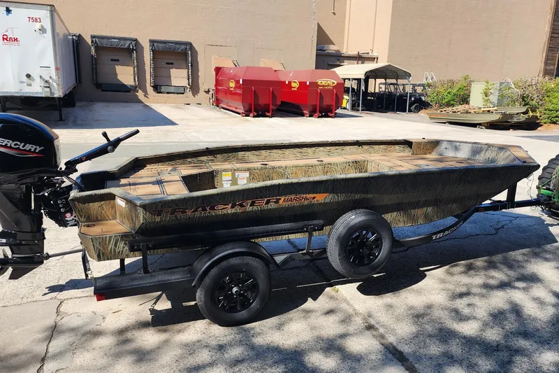 Slide: The Image of 2026 Tracker Grizzly 1756 T Marsh boat on trailer, parked outdoors in industrial area. - 2