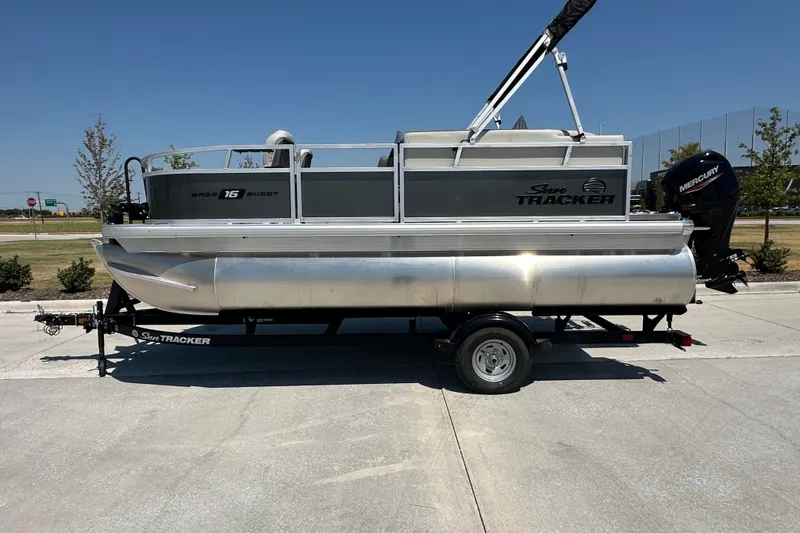 The Image of 2026 Sun Tracker Bass Buggy 16 XL Select pontoon boat on trailer, outdoor setting. - 1