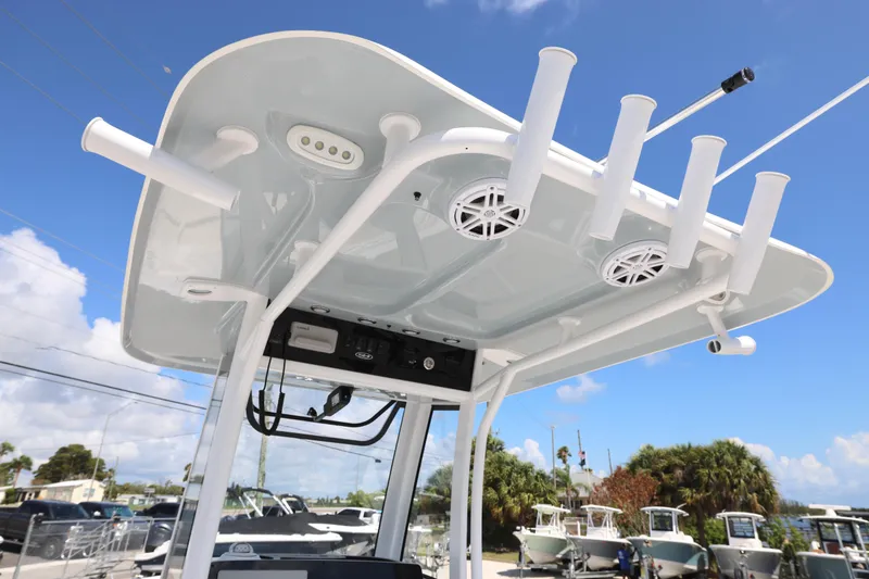Slide: The Image of 2026 Sea Hunt Ultra 239 SE boat with T-top, rod holders, and speakers under a clear sky. - 7