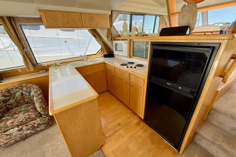 Slide: The Image of 1997 Navigator Pilothouse yacht kitchen with wood cabinetry, stove, microwave, and refrigerator. - 14
