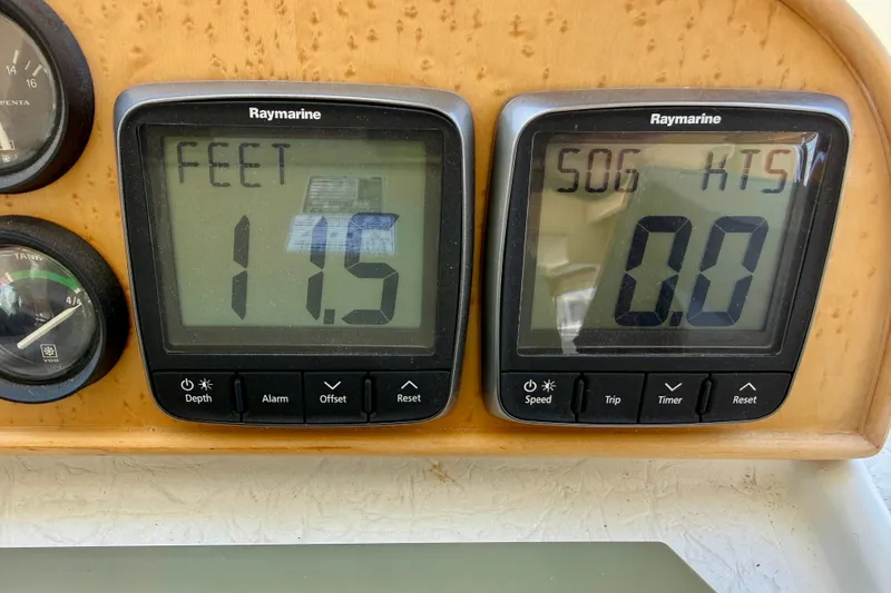 Slide: The Image of Boat dashboard with Raymarine displays showing depth 11.5 feet and speed 0.0 knots. Navigator Pilothouse 1997. - 27