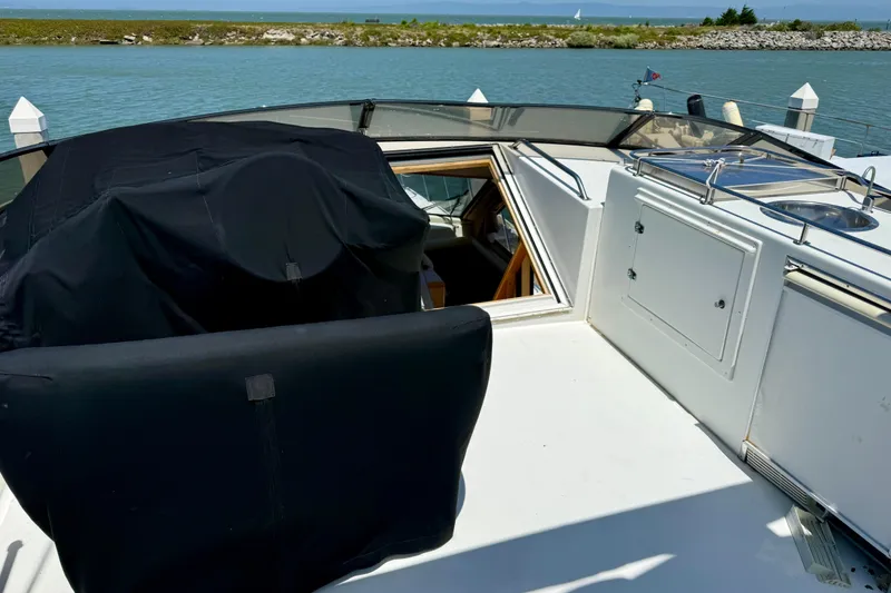 Slide: The Image of 1997 Navigator Pilothouse yacht deck with covered equipment and open hatch, docked by the water. - 31
