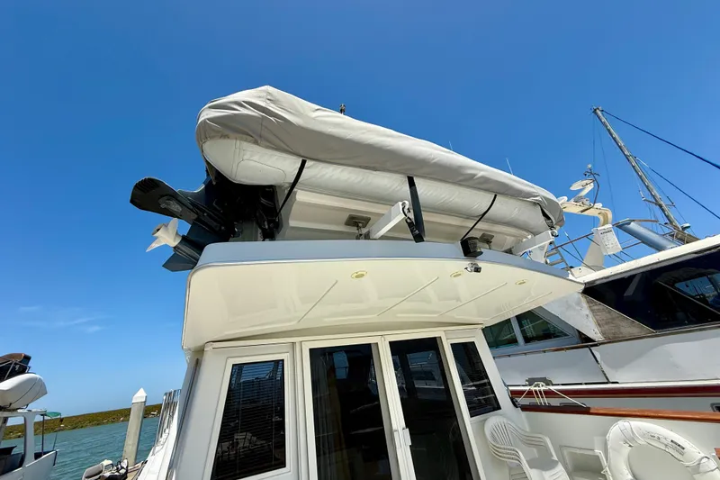 Slide: The Image of 1997 Navigator Pilothouse yacht with covered dinghy on top, docked under clear blue sky. - 4