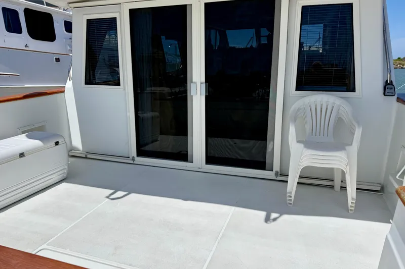 Slide: The Image of 1997 Navigator Pilothouse yacht deck with sliding glass doors and stacked white chairs. - 7